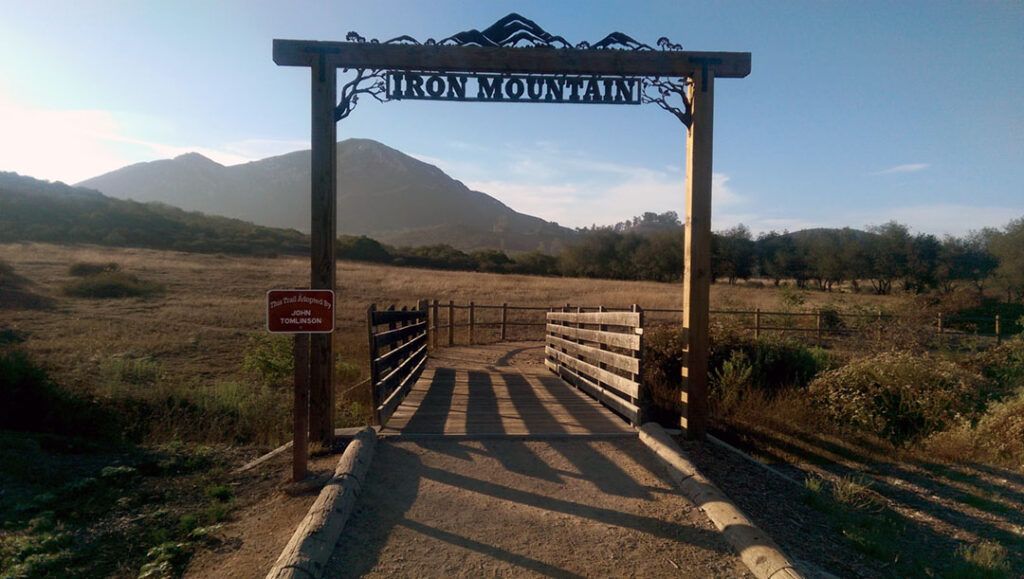 A rot iron sign and wooden bridge at Iron Mountain trailhead