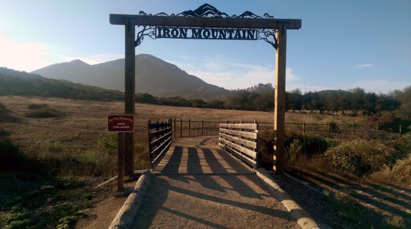 A rot iron sign and wooden bridge at Iron Mountain trailhead