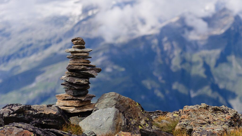 A rock cairn with cloud covered mountains behind