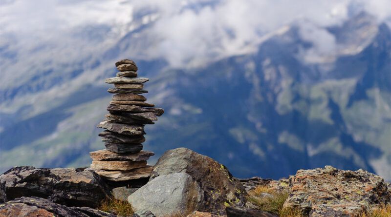 A rock cairn with cloud covered mountains behind