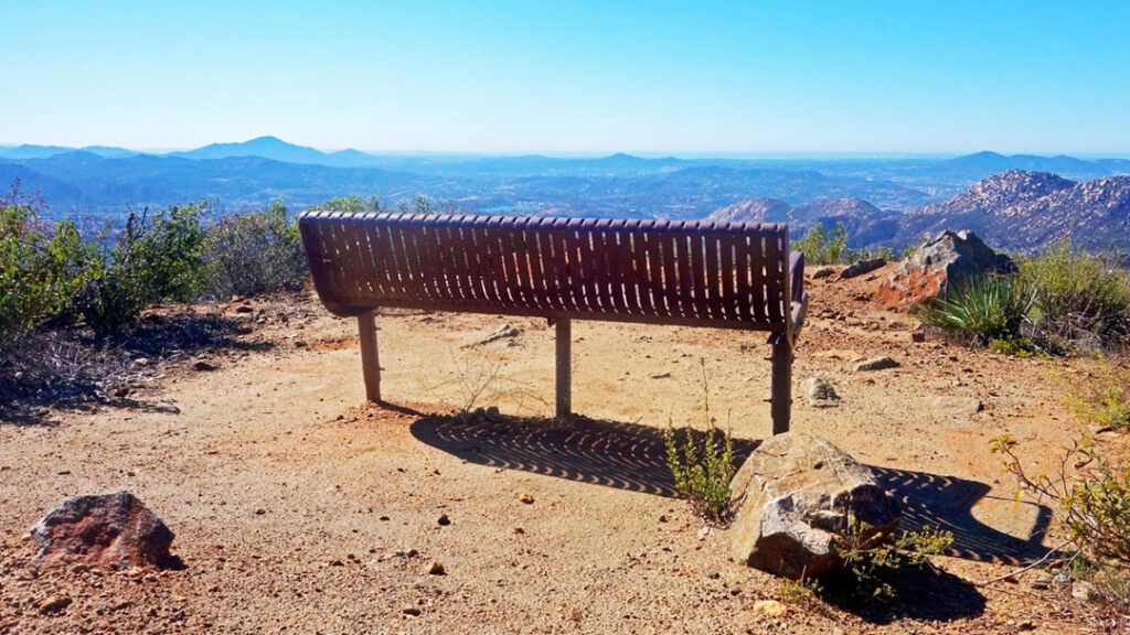 A park bench sits atop a hill overlooking the scenic landscape below.