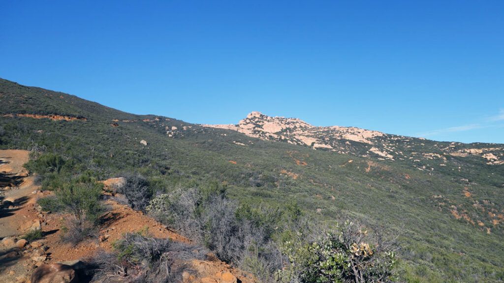 A first glimpse of Lawson Peak appears over the hills from the trail.