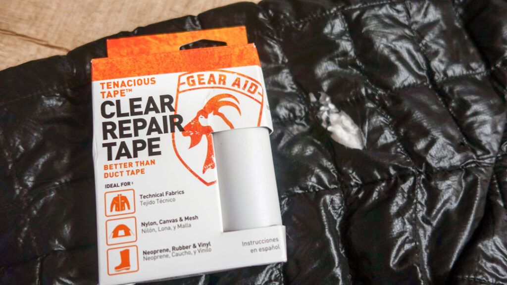 Gear Aid repair tape sits on a puffer jacket in need of repair.