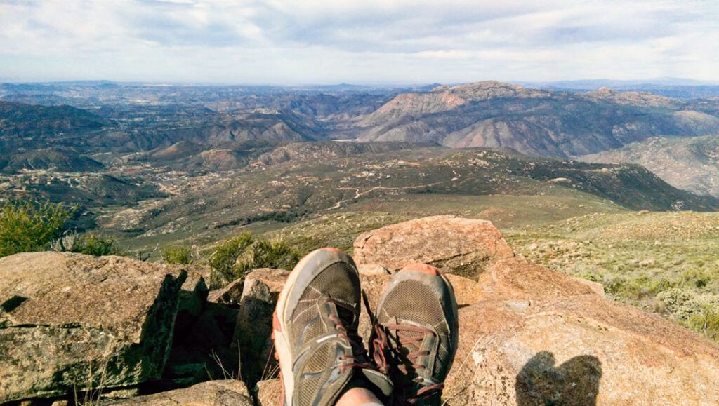 Looking over a hiker's shoes into the valley from the summit of Viejas Mountain trail