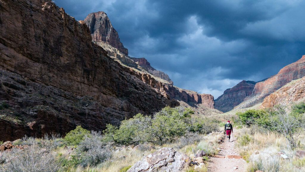 Fabian hiking on North Kaibab trail with storm clouds looming overhead.
