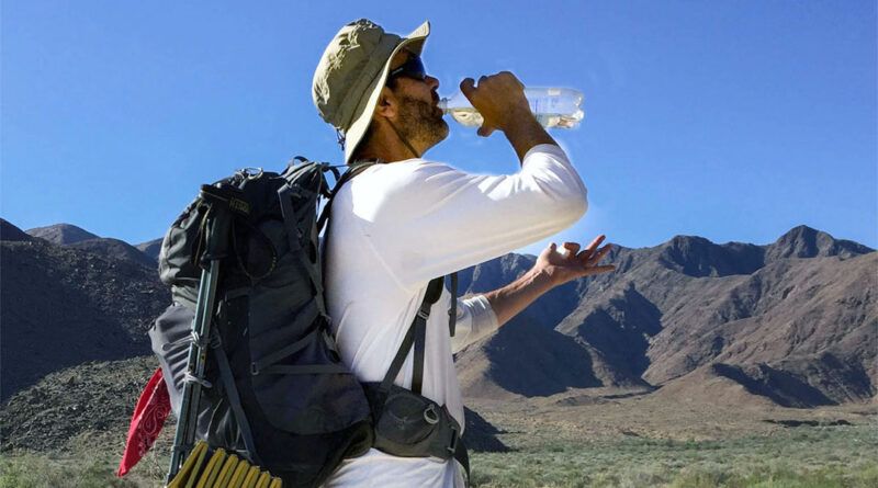Hiker drinking water from a water bottle in the desert.