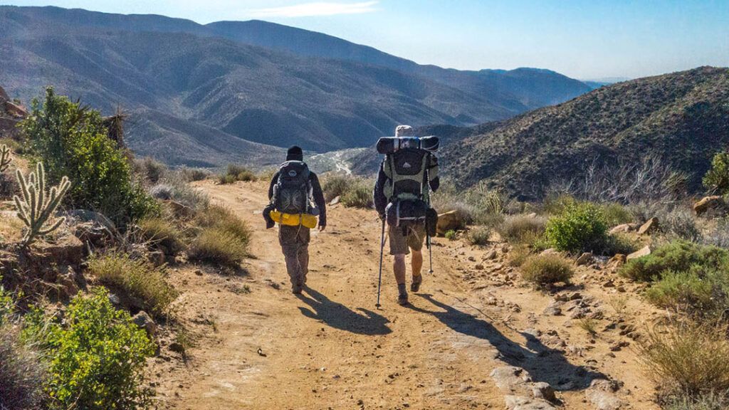 Two backpackers hiking on the trail down into Coyote Canyon.